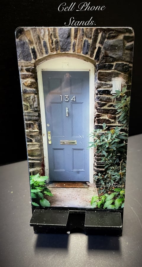 Cell phone stand shaped like a blue door numbered 134 in a stone archway with climbing ivy