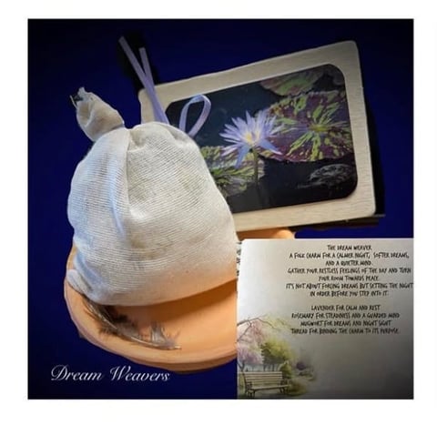Dream Weavers product display showing a white mesh dream catcher hanging from a wooden frame with instructional card and nature photograph on dark background