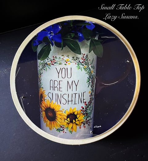 Small decorative table top with You are my Sunshine text, yellow sunflowers, and blue flowers in a white ceramic vase
